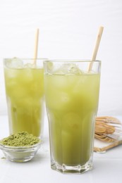 Delicious iced green matcha tea and powder on white table