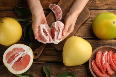 Photo of Woman with tasty red pomelo at wooden table, top view