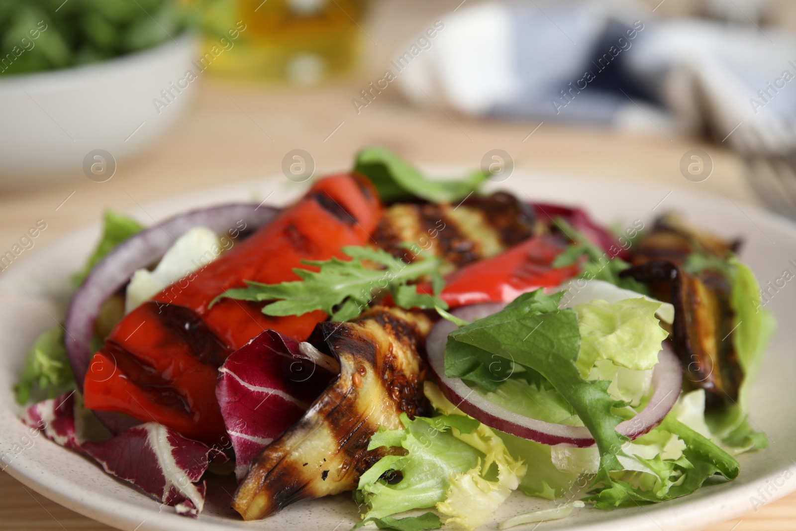 Photo of Delicious salad with roasted eggplant and arugula on plate, closeup