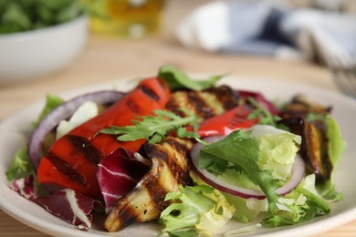 Photo of Delicious salad with roasted eggplant and arugula on plate, closeup