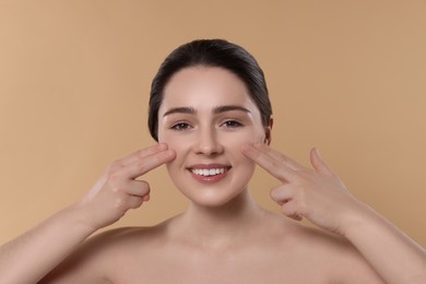 Photo of Young woman massaging her face on beige background