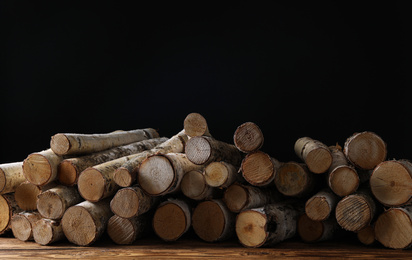 Photo of Cut firewood on table against black background