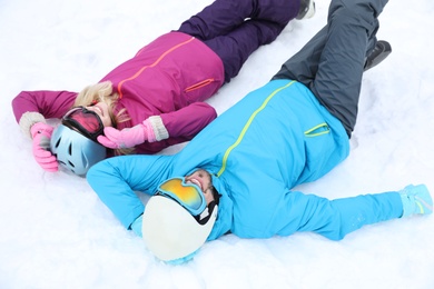 Couple lying on snow at ski resort. Winter vacation