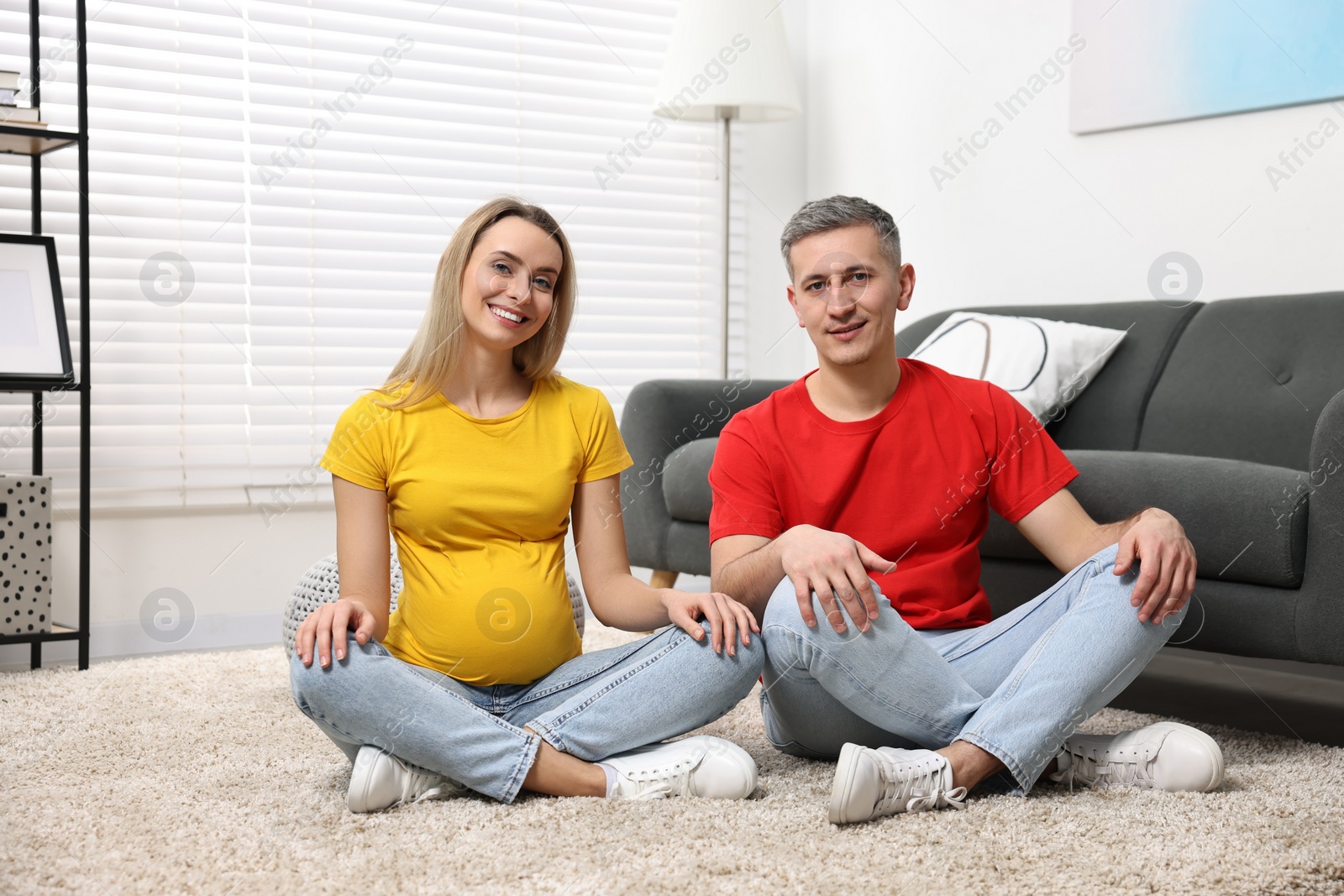 Photo of Young family housing concept. Pregnant woman with her husband on floor at home