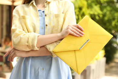 Young woman with elegant envelope bag outdoors on summer day, closeup