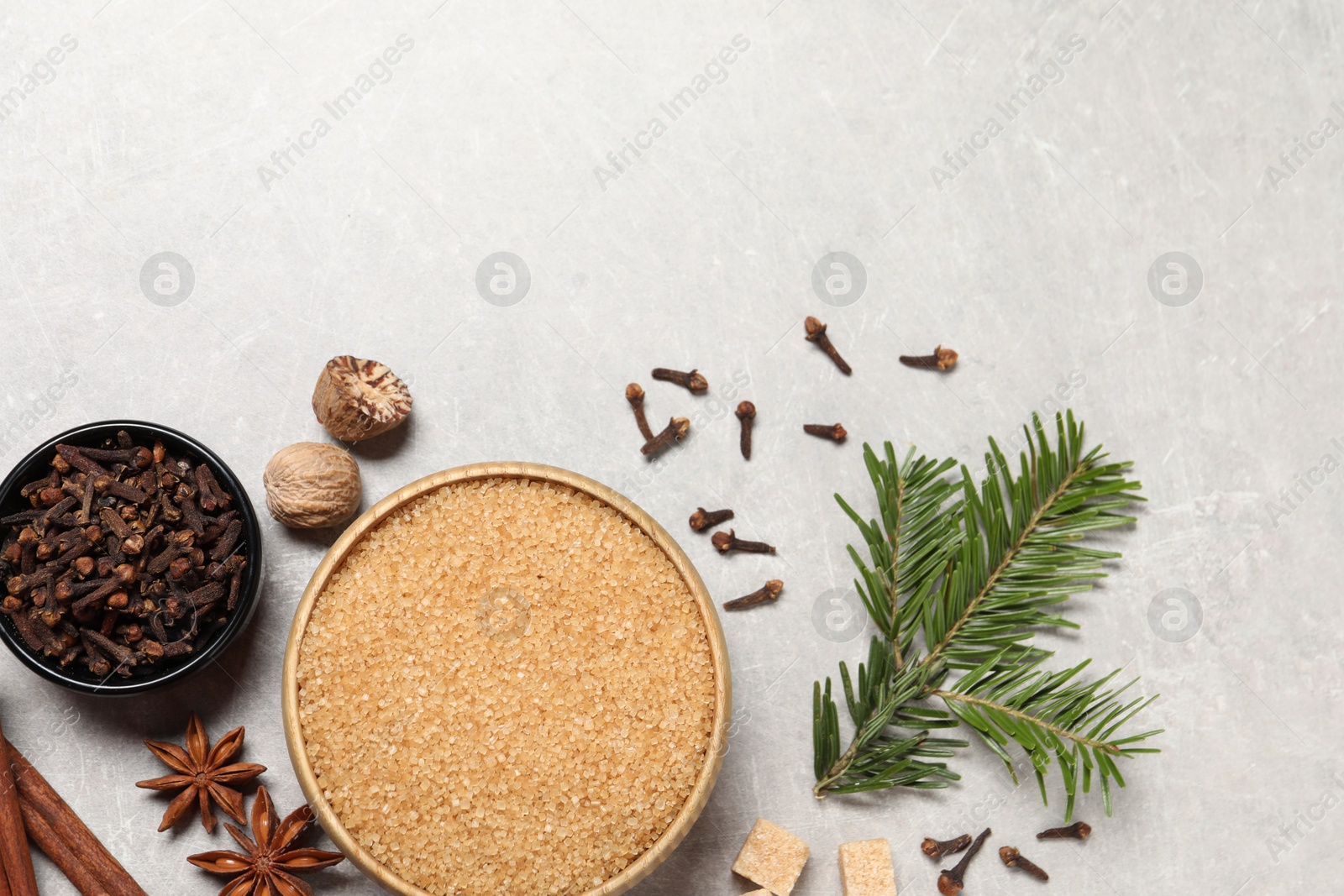 Photo of Different spices in bowls, nuts and fir branch on light gray textured table, flat lay. Space for text