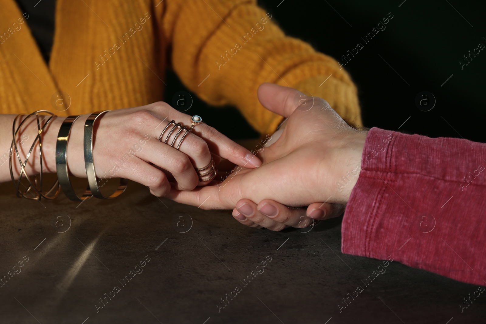 Photo of Chiromancer reading lines on man's palm at table, closeup