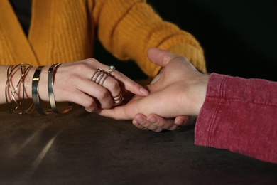 Chiromancer reading lines on man's palm at table, closeup