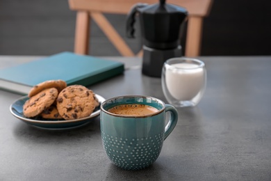 Cup of aromatic hot coffee and cookies on table