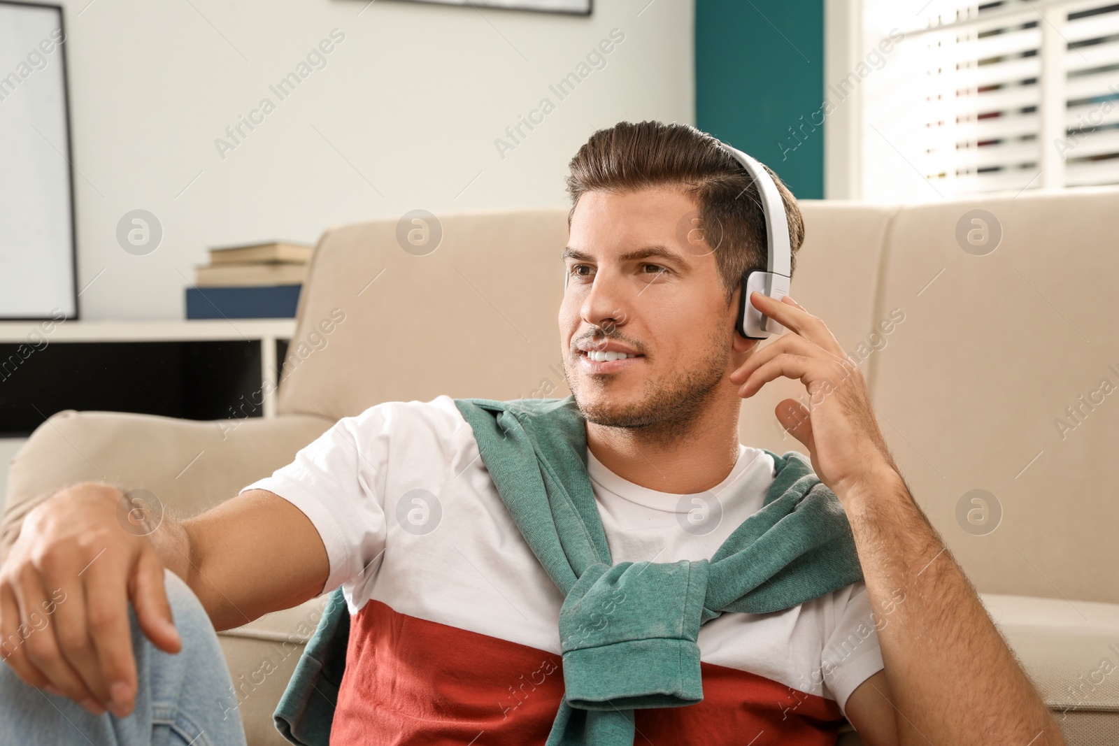 Photo of Man listening to audiobook near sofa at home