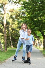 Photo of Mother and son roller skating in summer park