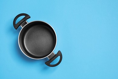 Empty pot on light blue background, top view. Space for text