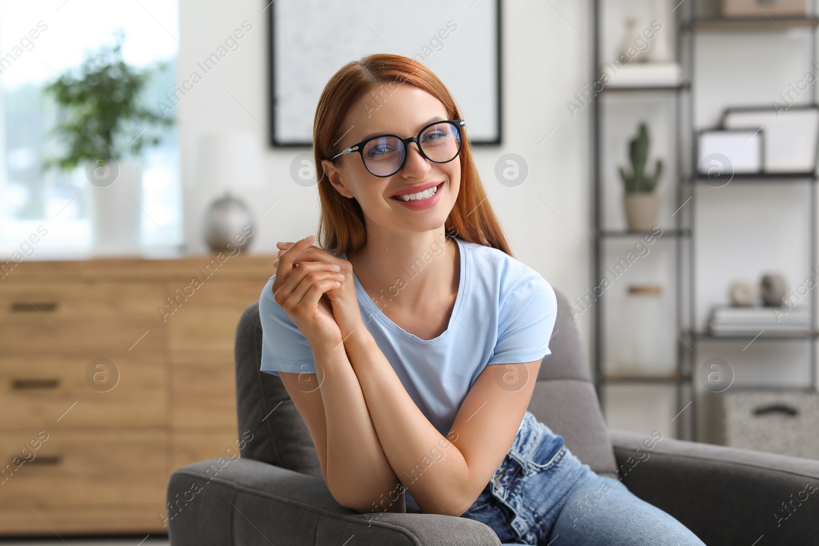 Photo of Portrait of beautiful young woman with red hair at home. Attractive lady smiling and looking into camera