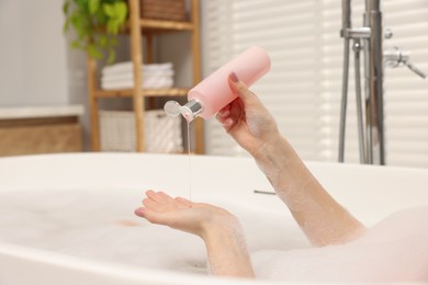 Photo of Woman pouring shower gel onto hand in bath indoors, closeup. Space for text