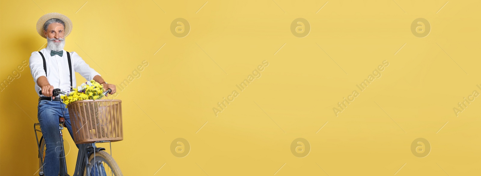 Image of Portrait of handsome mature man with bicycle on yellow background, space for text. Banner design