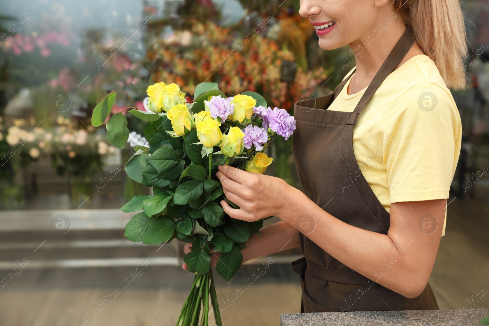 Photo of Female florist making beautiful bouquet in flower shop, closeup