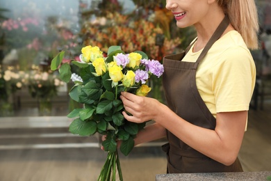 Photo of Female florist making beautiful bouquet in flower shop, closeup