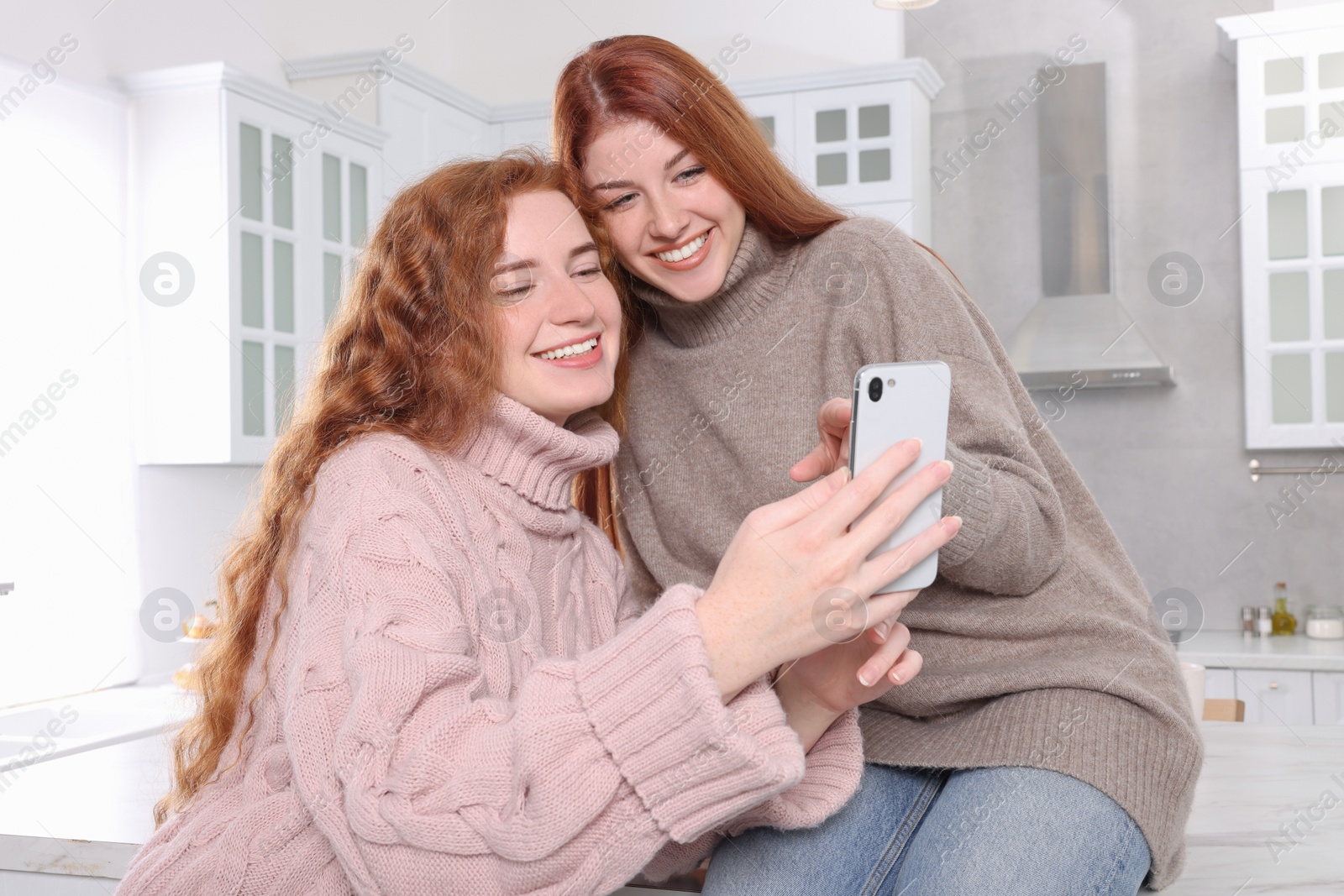 Photo of Beautiful young sisters spending time together in kitchen