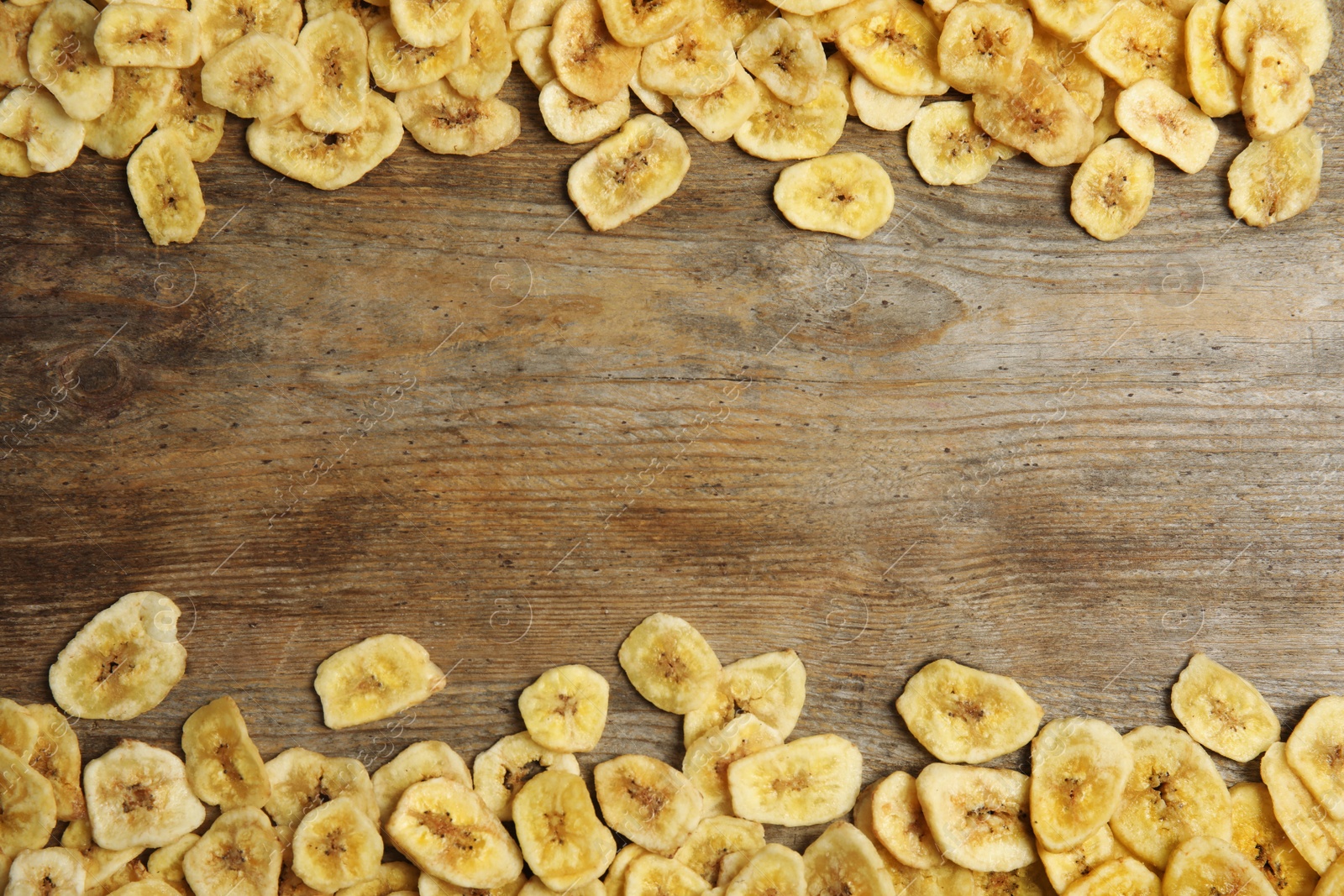 Photo of Frame made of sweet banana slices on wooden background, top view with space for text. Dried fruit as healthy snack