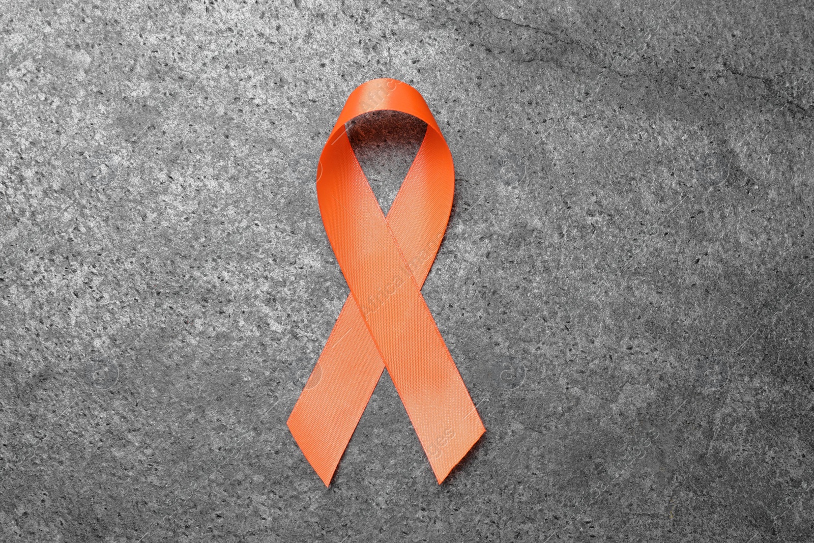 Photo of Orange ribbon on grey table, top view. Multiple sclerosis awareness