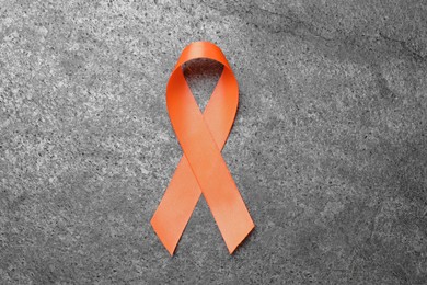 Photo of Orange ribbon on grey table, top view. Multiple sclerosis awareness