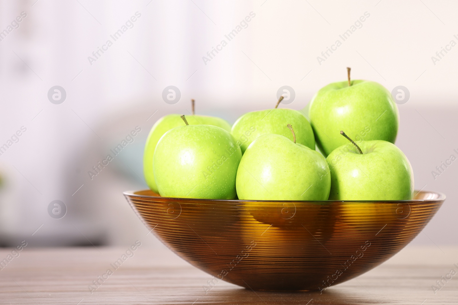 Photo of Bowl with sweet green apples on table against blurred background, closeup