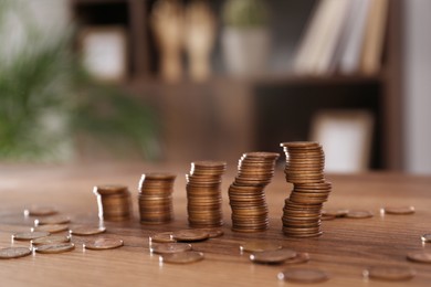 Photo of Stacks of coins on wooden table against blurred background
