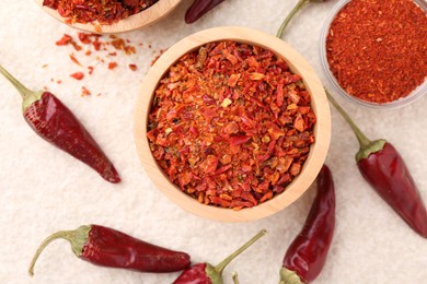 Chili pepper flakes and pods on light textured table, flat lay