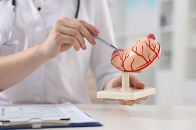 Gastroenterologist showing human stomach model at table in clinic, closeup