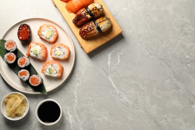 Delicious sushi rolls, soy sauce and ginger on light grey marble table, flat lay. Space for text