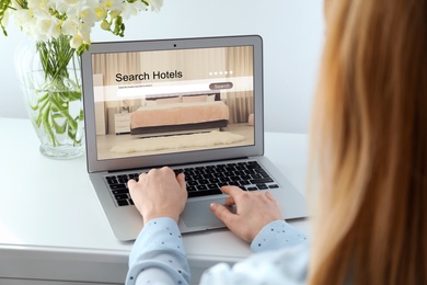 Woman searching hotel using laptop at table, closeup. Booking online service