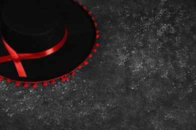 Photo of Black Flamenco hat on dark textured table, above view. Space for text