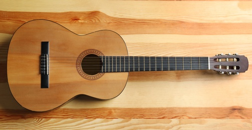 Photo of Beautiful classical guitar on wooden background, top view