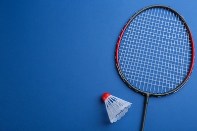 Photo of Badminton racket and shuttlecock on blue background, flat lay. Space for text