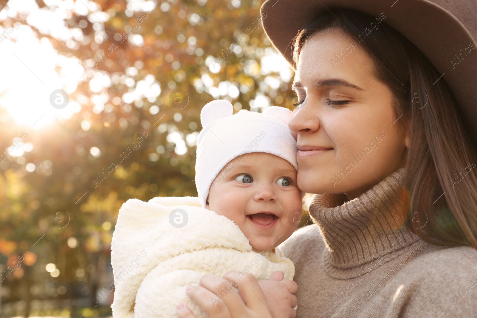 Photo of Happy mother with her baby daughter outdoors on autumn day, space for text