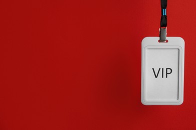 White plastic vip badge hanging on red background, space for text