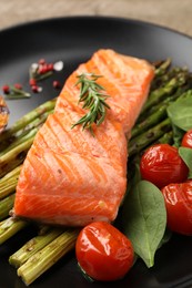 Tasty grilled salmon with tomatoes, asparagus, spices on plate, closeup