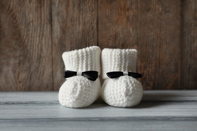 Handmade baby booties on table against wooden background