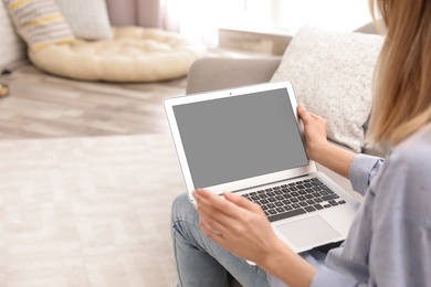 Photo of Young woman using video chat on laptop in living room, closeup. Space for design