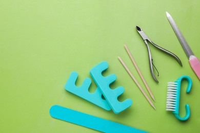 Photo of Set of pedicure tools on light green background, flat lay. Space for text