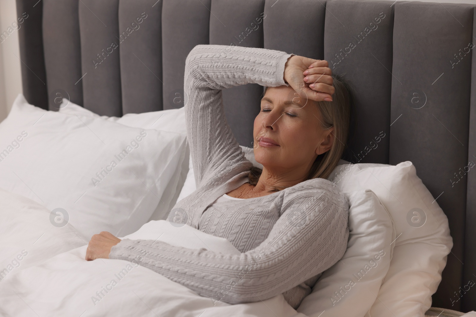 Photo of Menopause. Woman suffering from headache in bed indoors