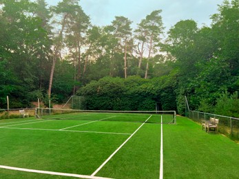 Photo of Tennis court with green grass and net outdoors