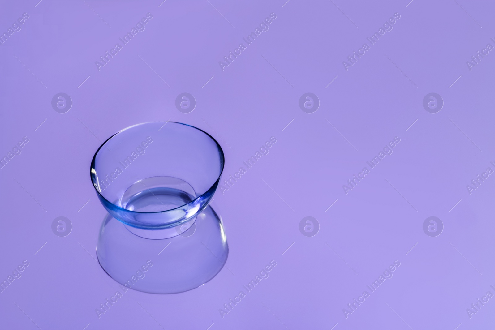 Photo of One contact lens on violet reflective surface