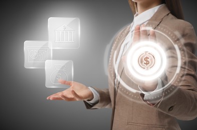 Budget management. Businesswoman using virtual screen with financial icons on gray background, closeup
