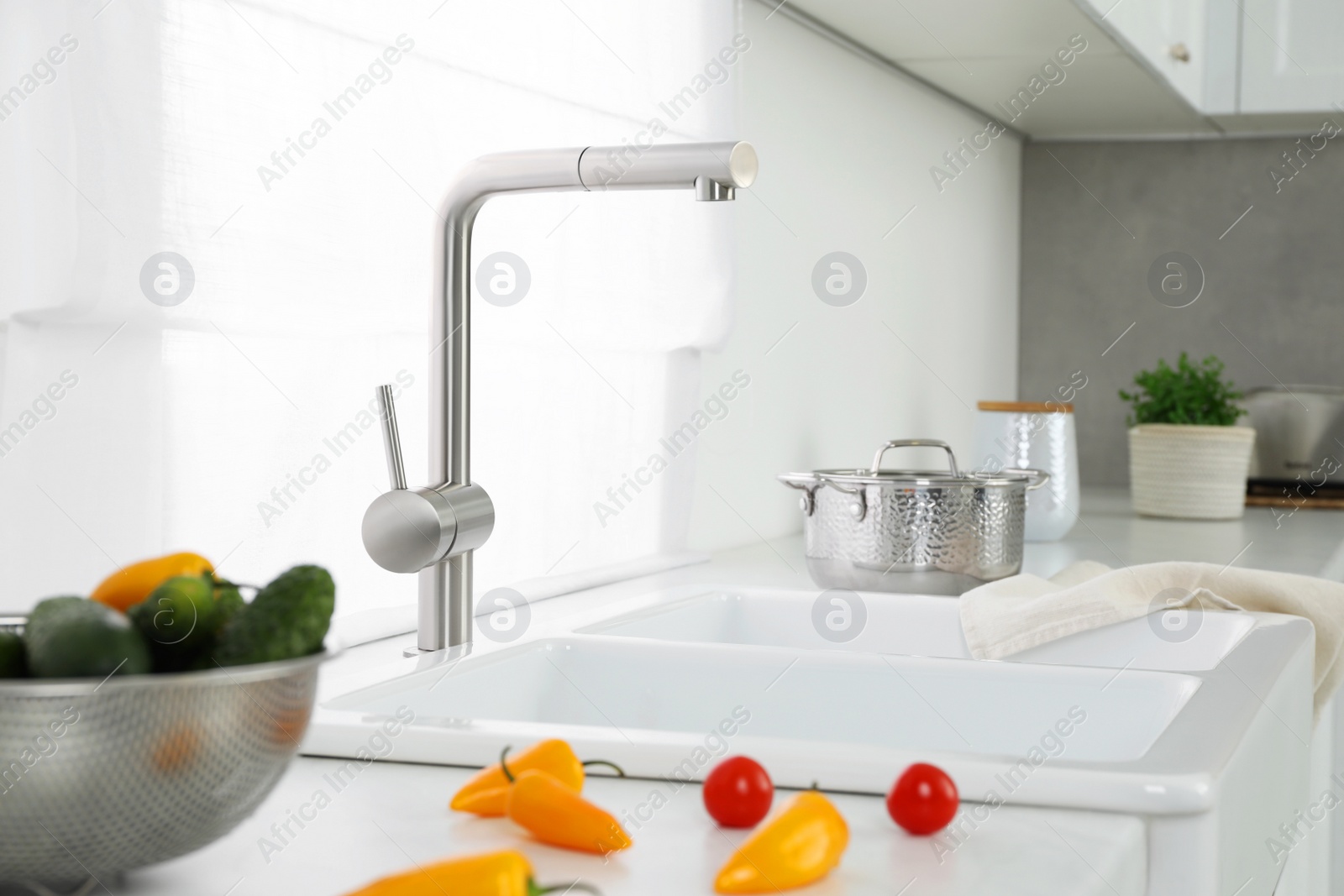 Photo of Fresh clean vegetables on kitchen counter near sink