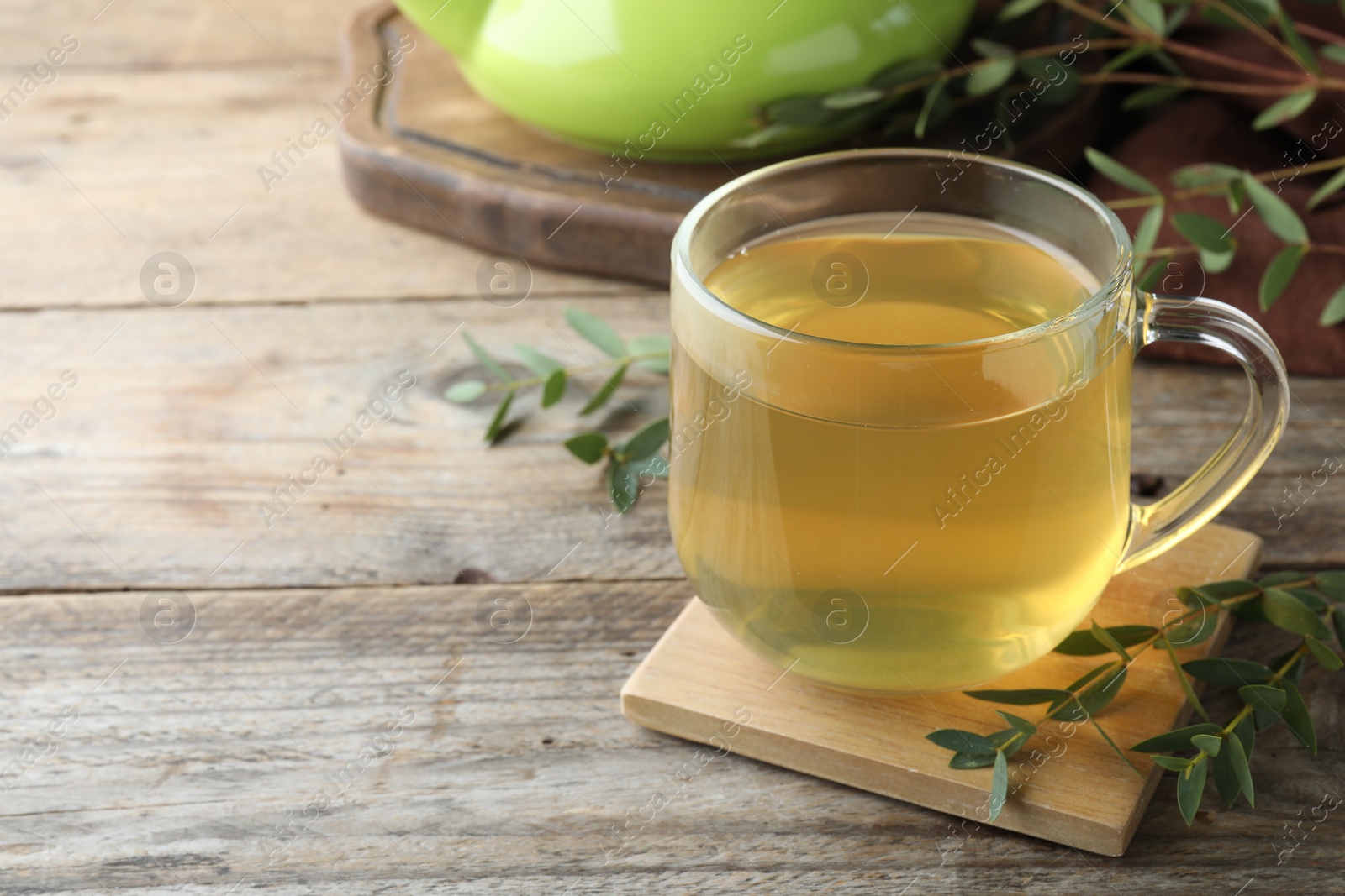 Photo of Glass cup of aromatic eucalyptus tea on wooden table, closeup. Space for text