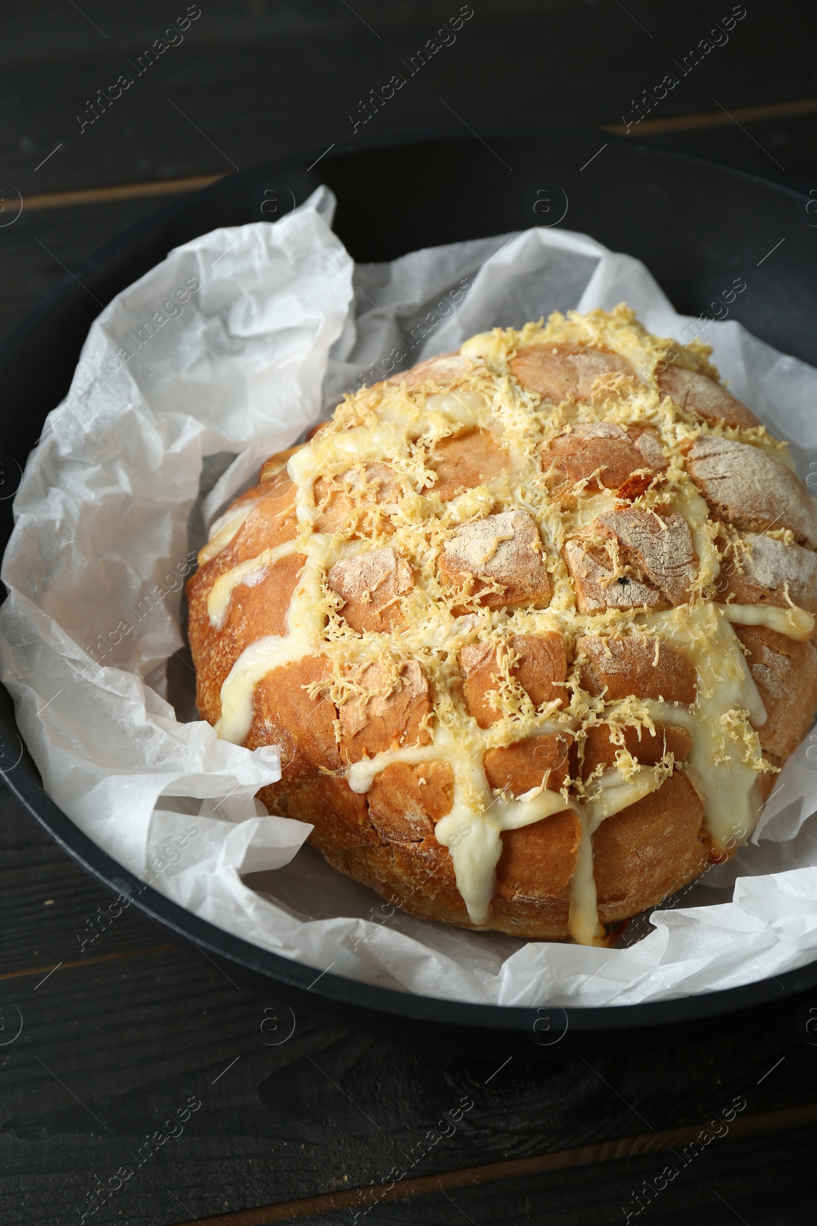 Photo of Freshly baked bread with tofu cheese and lemon zest on black wooden table