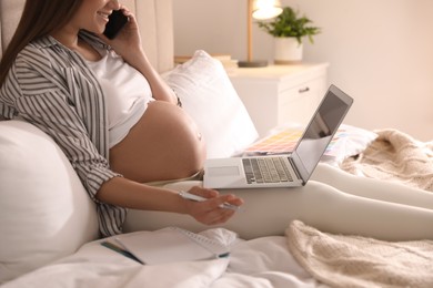 Pregnant woman working on bed at home, closeup. Maternity leave