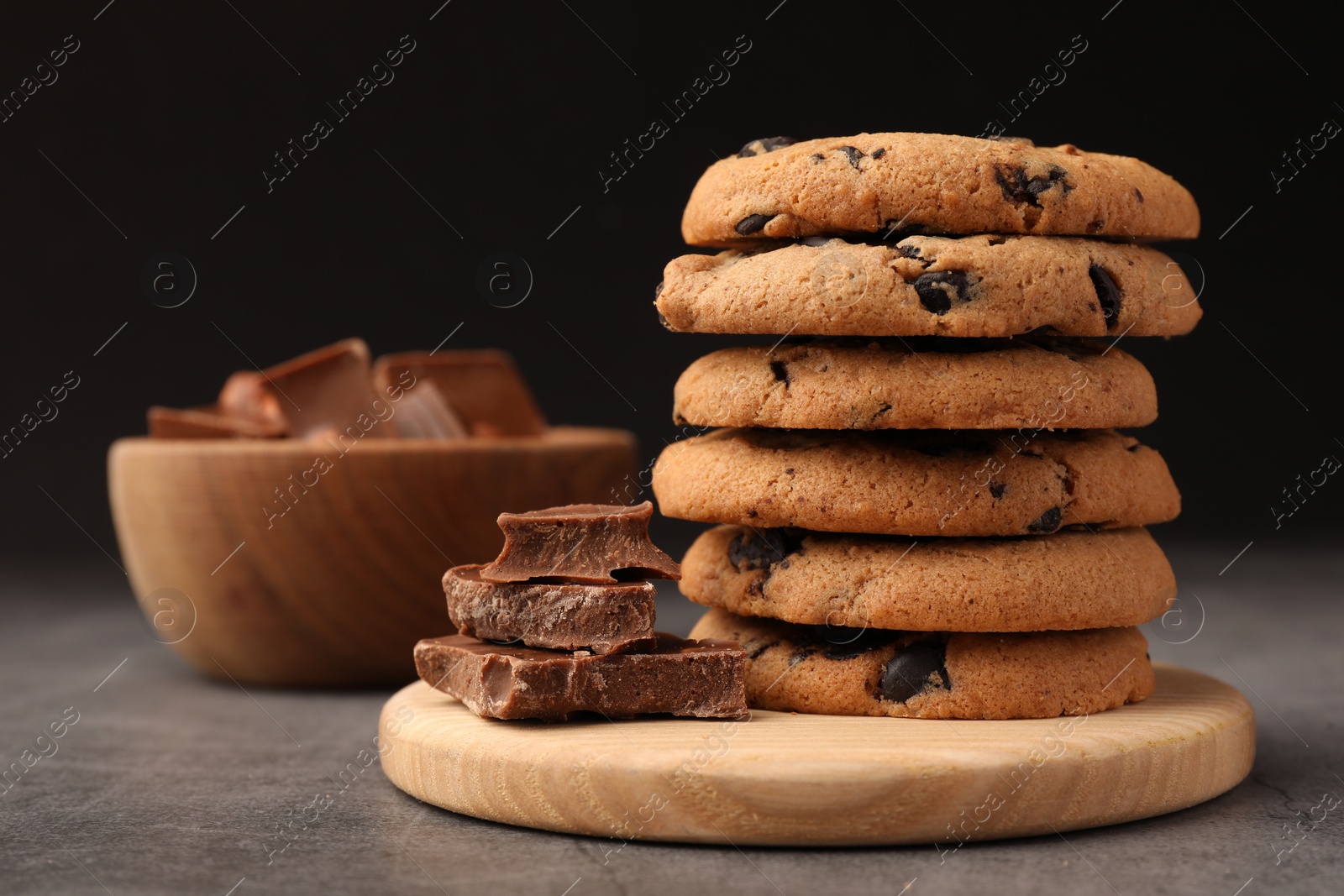 Photo of Stack of delicious chocolate chip cookies on grey table, closeup