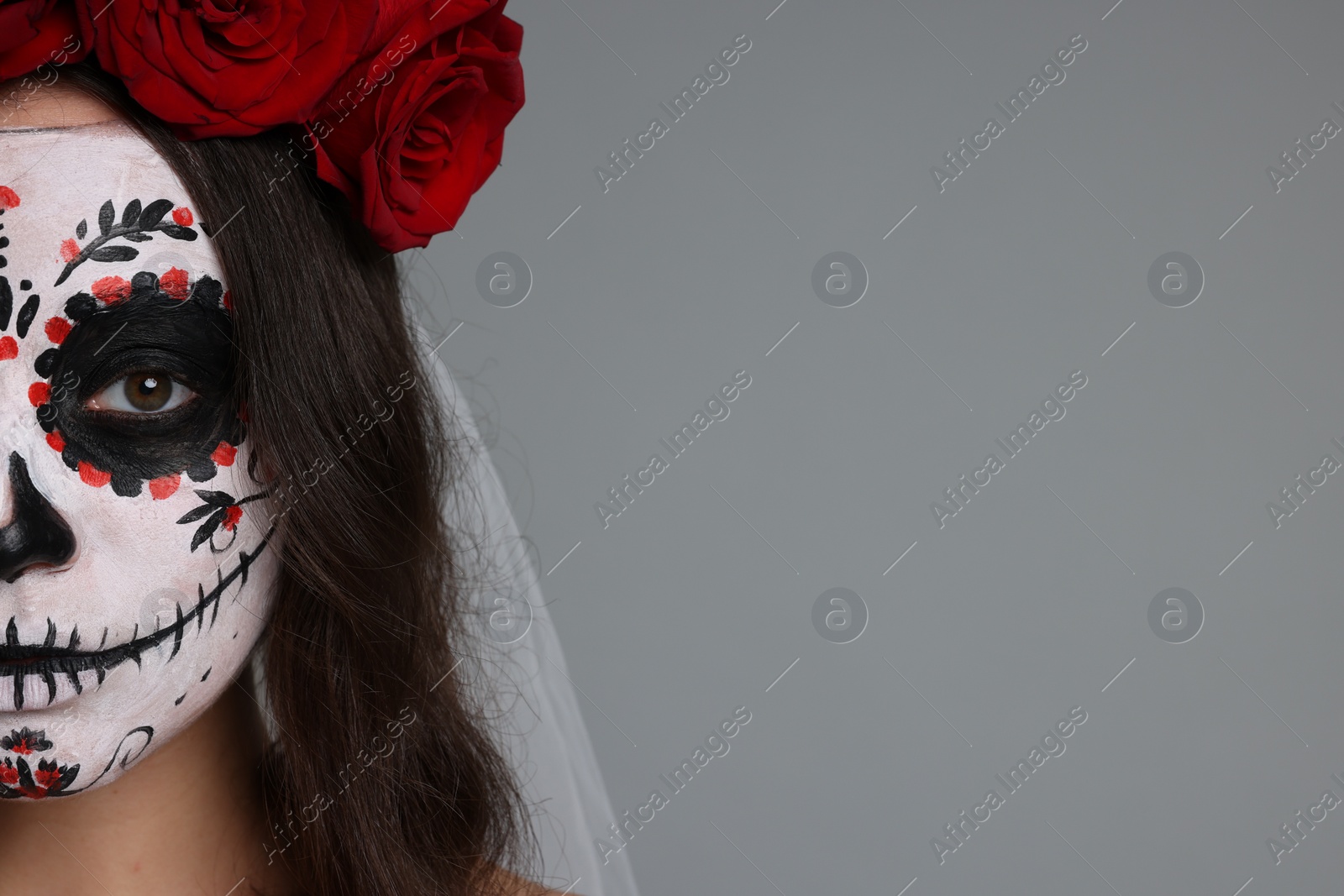 Photo of Young woman in scary bride costume with sugar skull makeup and flower crown on light grey background, closeup and space for text. Halloween celebration